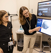 Debra Kahn (left) and Katharine Marder (right) view an image on the transcranial magnetic stimulation device.